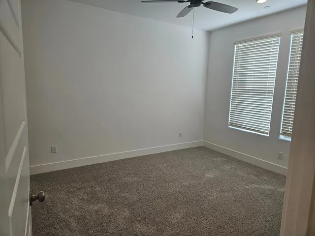 an empty room with a window and a ceiling fan