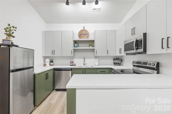 a kitchen with stainless steel appliances a refrigerator a stove a sink and white cabinets