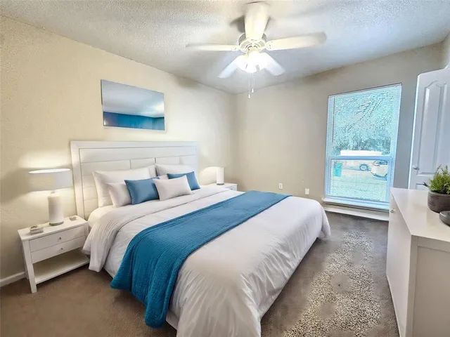 an empty room with a chandelier fan and windows