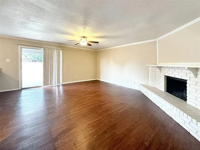 a view of an empty room with a fireplace and wooden floor