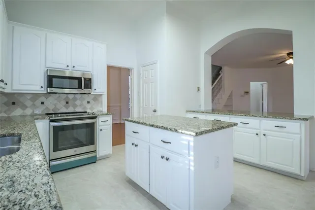 a kitchen with granite countertop a stove top oven microwave and cabinets