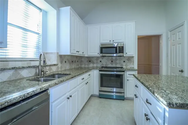 a kitchen with granite countertop a sink stove and cabinets