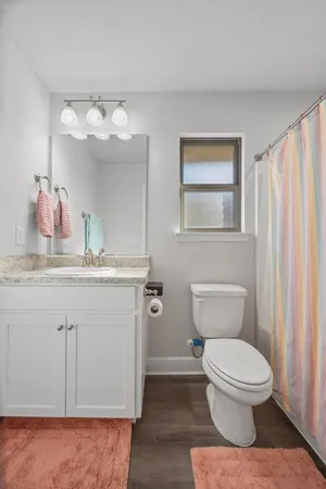 a bathroom with a granite countertop toilet sink and mirror