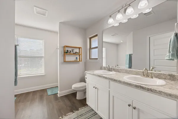 a bathroom with a granite countertop toilet a sink and a mirror