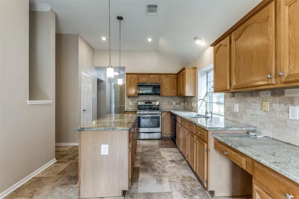 a kitchen with kitchen island granite countertop a sink a counter top space stainless steel appliances and cabinets