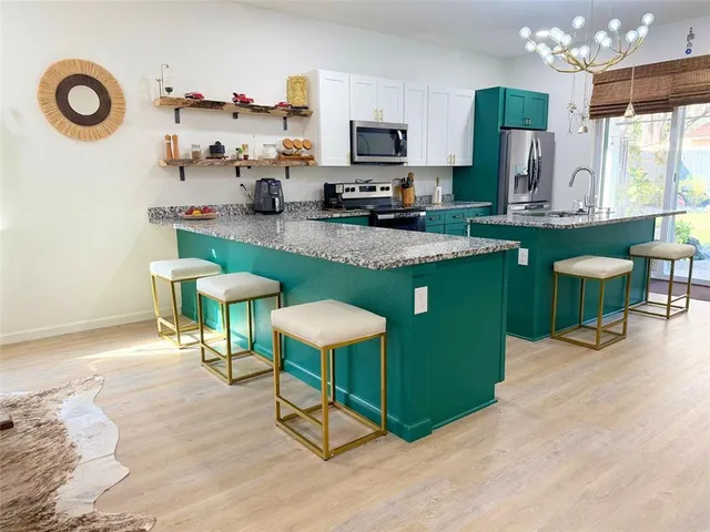 a kitchen with stainless steel appliances granite countertop a stove top oven a sink dishwasher and a dining table with wooden floor