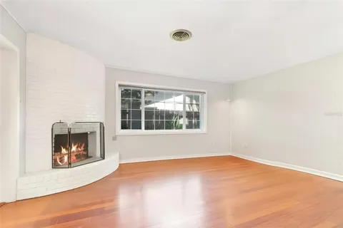 a view of an empty room with a window and fireplace