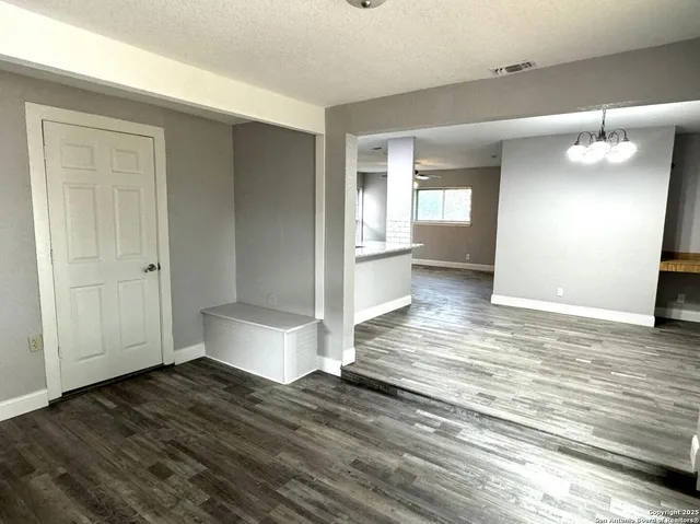 a view of a hallway to a room with wooden floor and cabinet