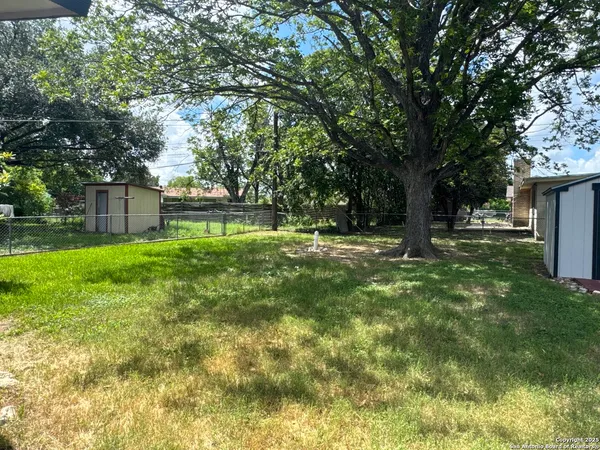 a backyard of a house with lots of plants and large tree