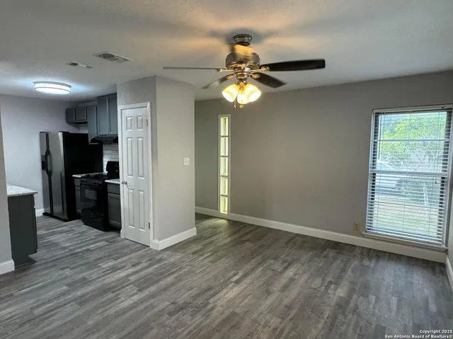a view of an empty room with a window and wooden floor