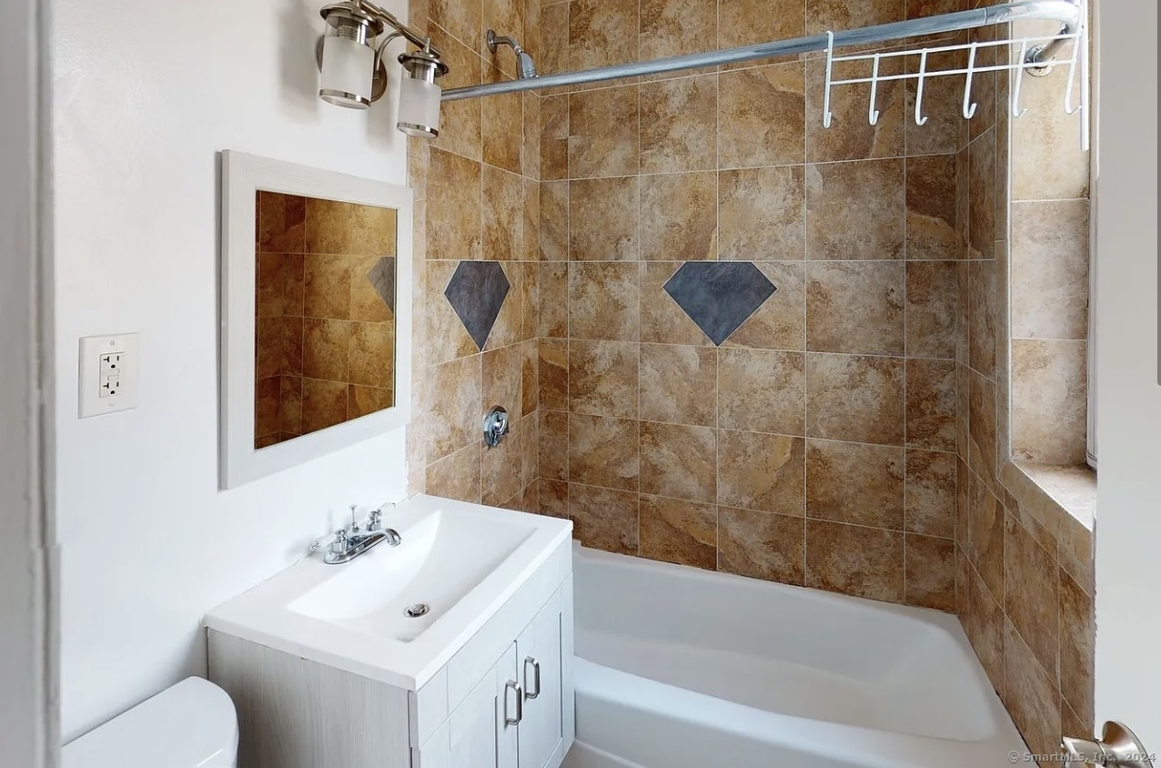 335 Wells Street, Unit 18 Bridgeport, CT 06606 - Photo 3 of 4 a bathroom with a bathtub shower sink vanity and toilet
