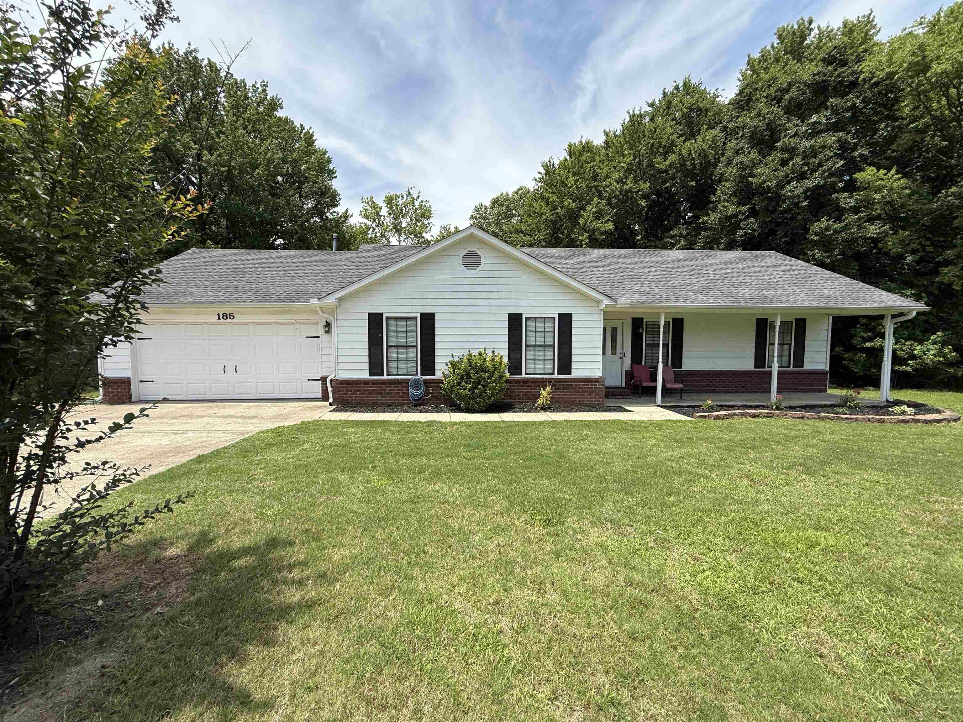 185 Mignon Road Atoka, TN 38004 - Photo 2 of 34 Ranch-style residence featuring white siding, a two-car garage, a covered front porch with white columns, dark shutters, and a well-maintained front lawn