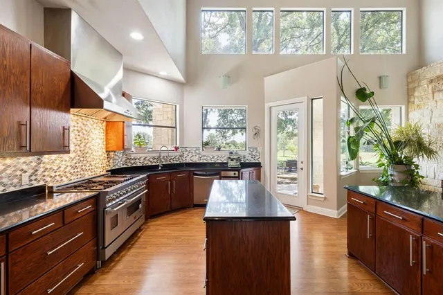 a large kitchen with stainless steel appliances kitchen island a large counter top space and wooden floor