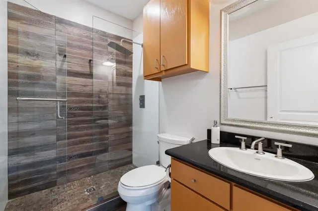 a bathroom with a granite countertop toilet sink and mirror