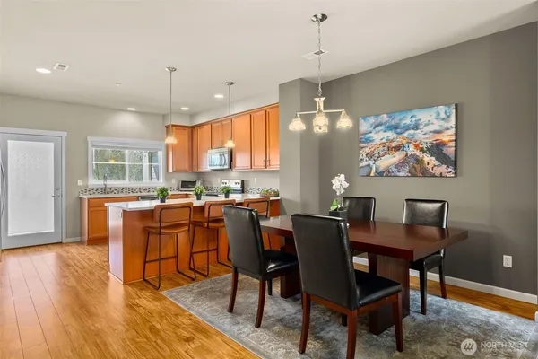 a kitchen with stainless steel appliances granite countertop wooden cabinets a stove a sink a dining table and chairs