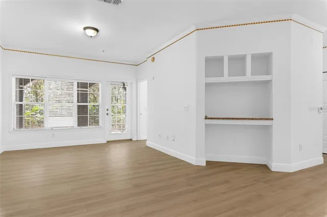 a view of an empty room with a window and wooden floor