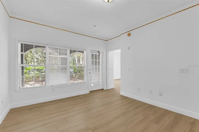 a view of an empty room with wooden floor and a window