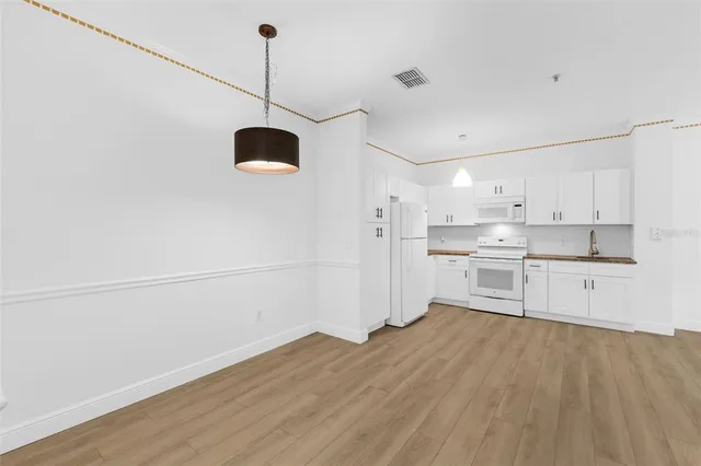 a kitchen with stainless steel appliances granite countertop a refrigerator a sink dishwasher a stove and white countertops with wooden floor