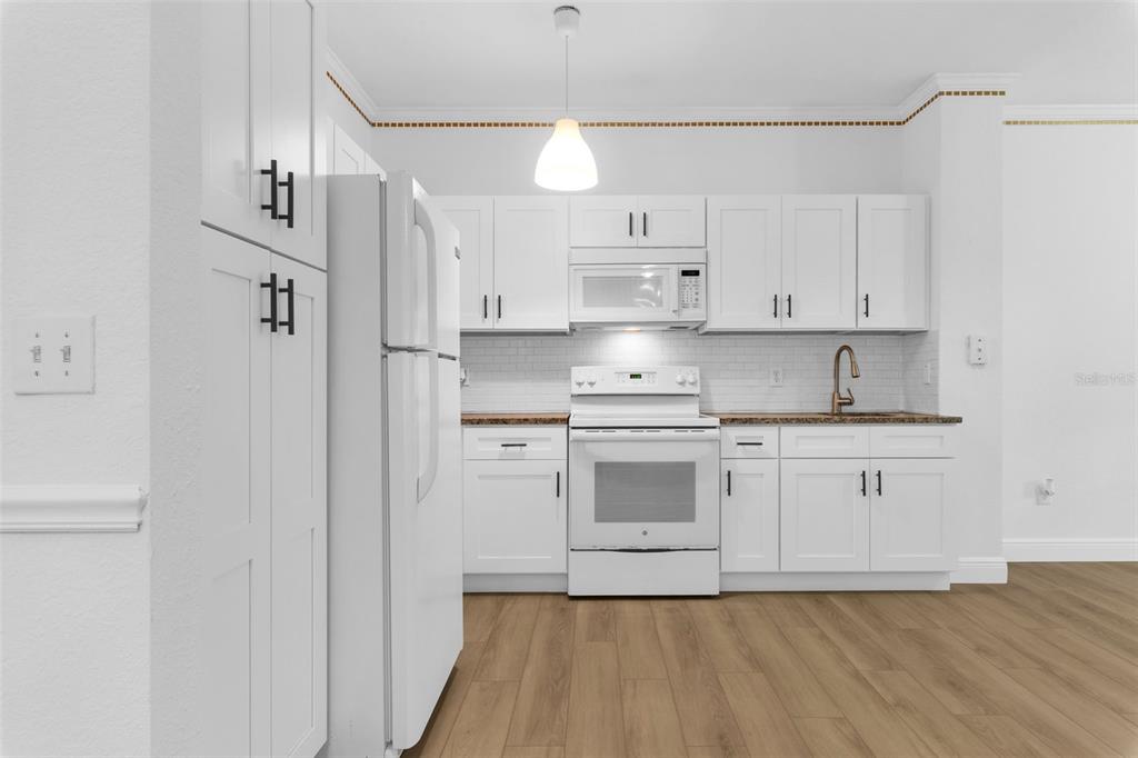 3561 Conroy Road, Unit 216 Orlando, FL 32839 - Photo 10 of 32 a kitchen with kitchen island granite countertop white cabinets white stainless steel appliances and sink