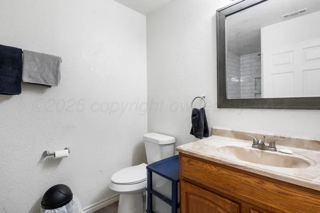 a bathroom with a granite countertop toilet sink and mirror