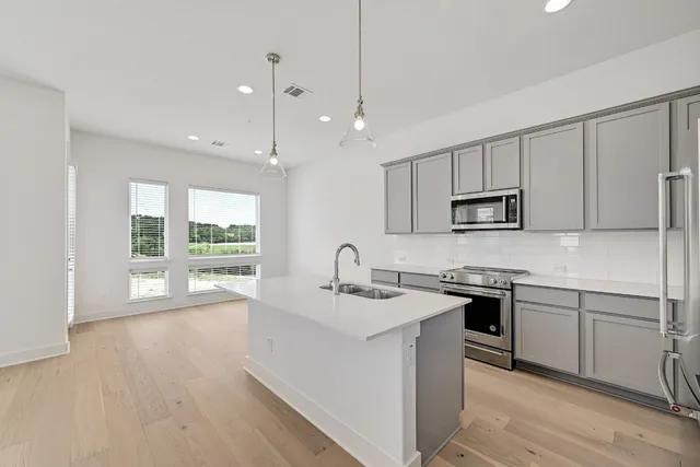 a kitchen with stainless steel appliances granite countertop a sink a oven a counter space and a window