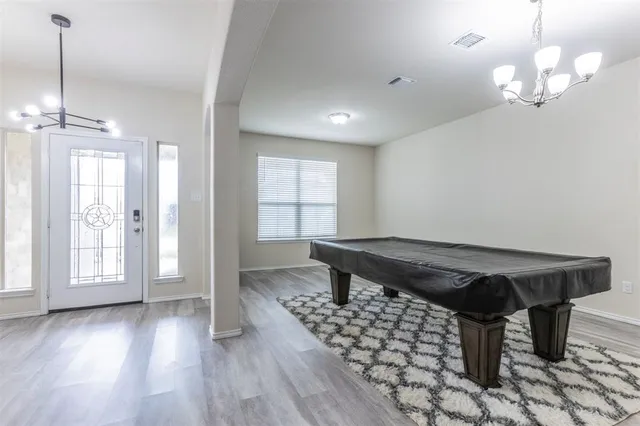 a dining room with wooden floor a chandelier a wooden table and chairs