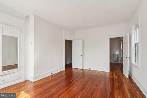 an empty room with wooden floor and window