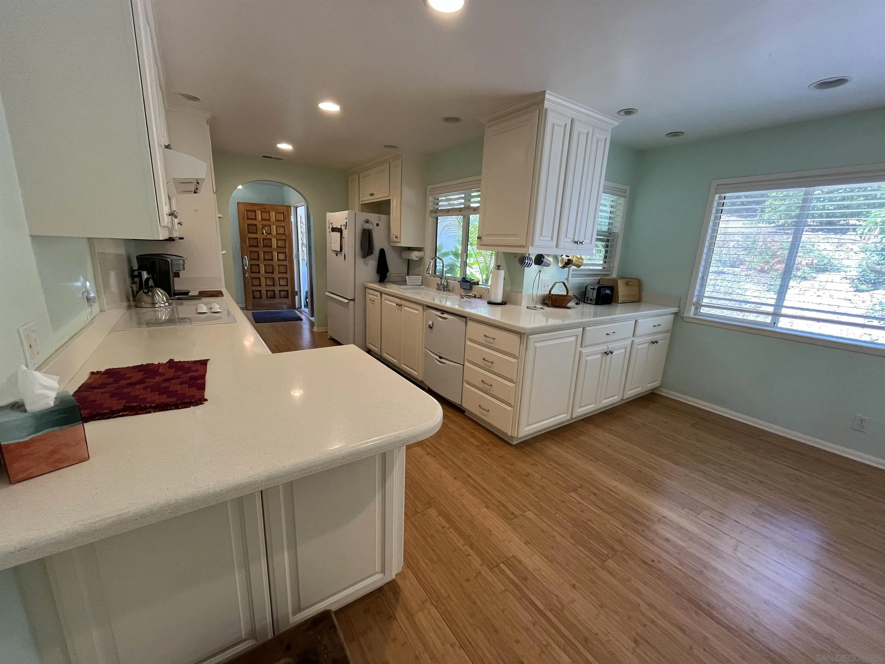 4688 Sun Valley Road Del Mar, CA 92014 - Photo 10 of 40 a large white kitchen with wooden floors and stainless steel appliances