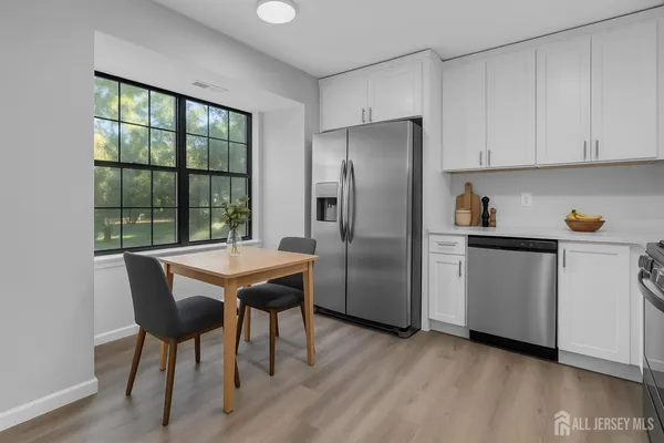 a kitchen with stainless steel appliances granite countertop a refrigerator a sink a stove a dining table and chairs