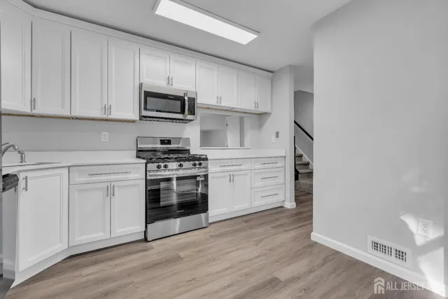 a kitchen with granite countertop white cabinets and stainless steel appliances