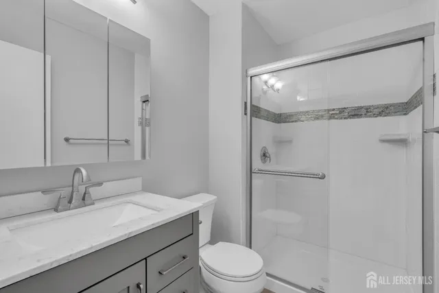 a bathroom with a granite countertop sink toilet a mirror and shower