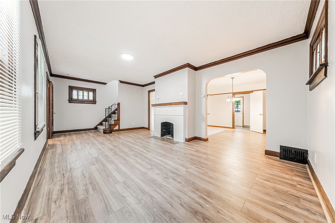 1271 Winston Road Cleveland, OH 44121 - Photo 8 of 43 Unfurnished living room featuring crown molding, arched walkways, light wood finished floors, and healthy amount of natural light