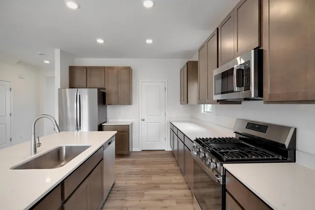 a kitchen with stainless steel appliances a sink a stove and cabinets
