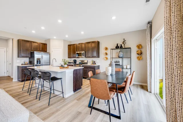 a dining room with stainless steel appliances a dining table chairs and a refrigerator