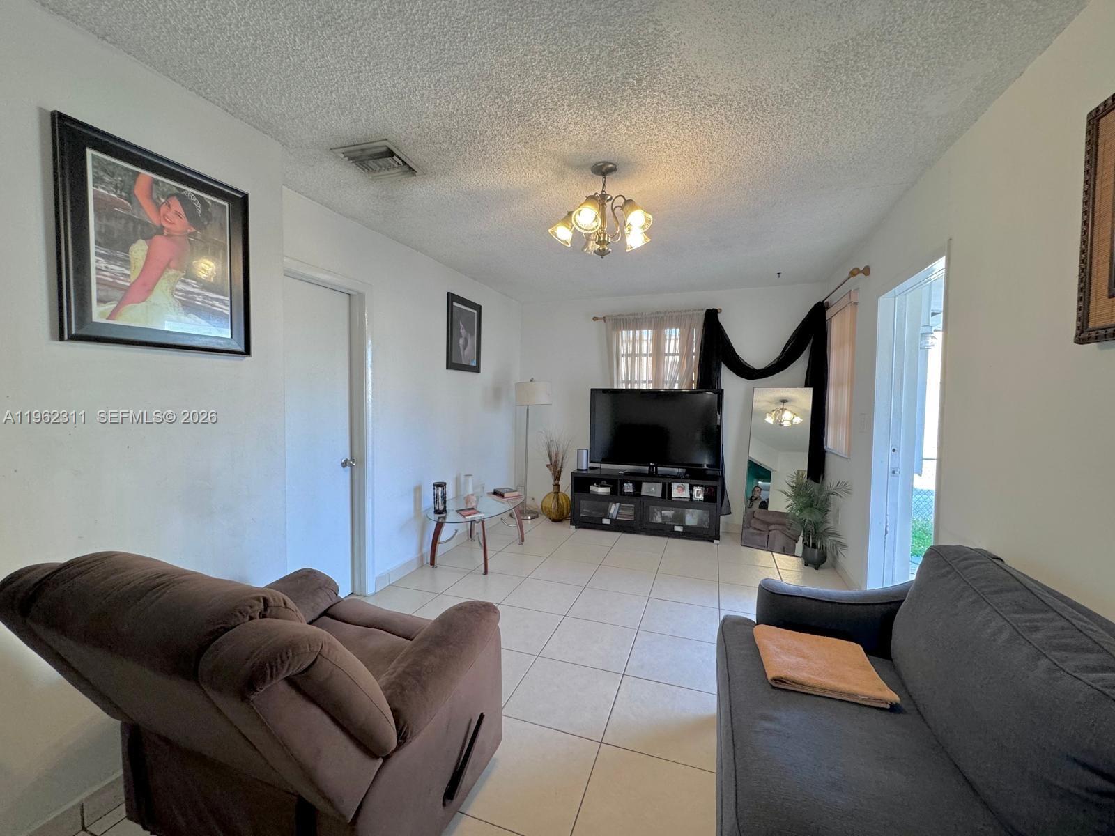 367 East 20th Street, Unit 369 Hialeah, FL 33010 - Photo 4 of 10 a living room with furniture a flat screen tv and a fireplace