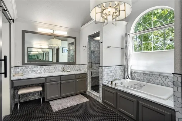 a bathroom with a granite countertop sink a large mirror and a bathtub next to a window