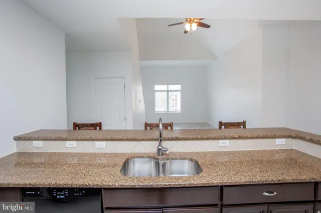 a kitchen with granite countertop a sink a counter top space and cabinets