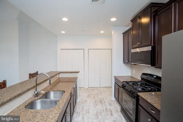 a kitchen with stainless steel appliances granite countertop a sink stove and refrigerator
