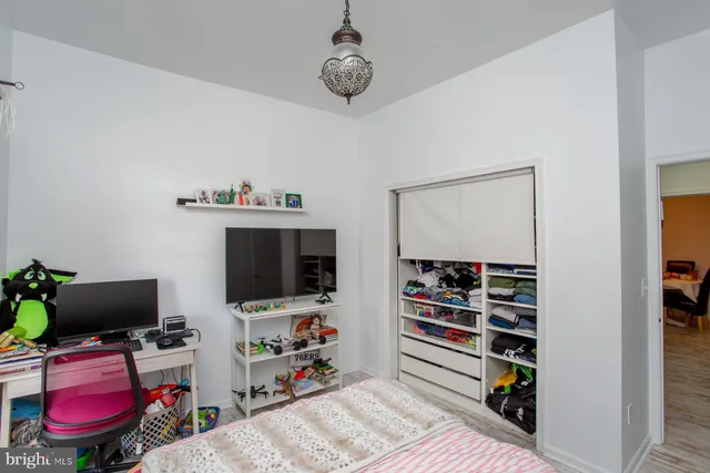 a bedroom with a bed and a potted plant on the dresser