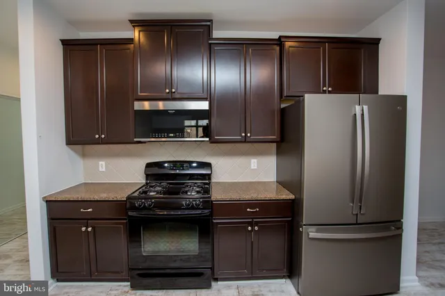 a kitchen with stainless steel appliances granite countertop a refrigerator and a stove
