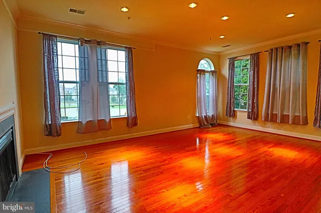 a view of an empty room with window and wooden floor
