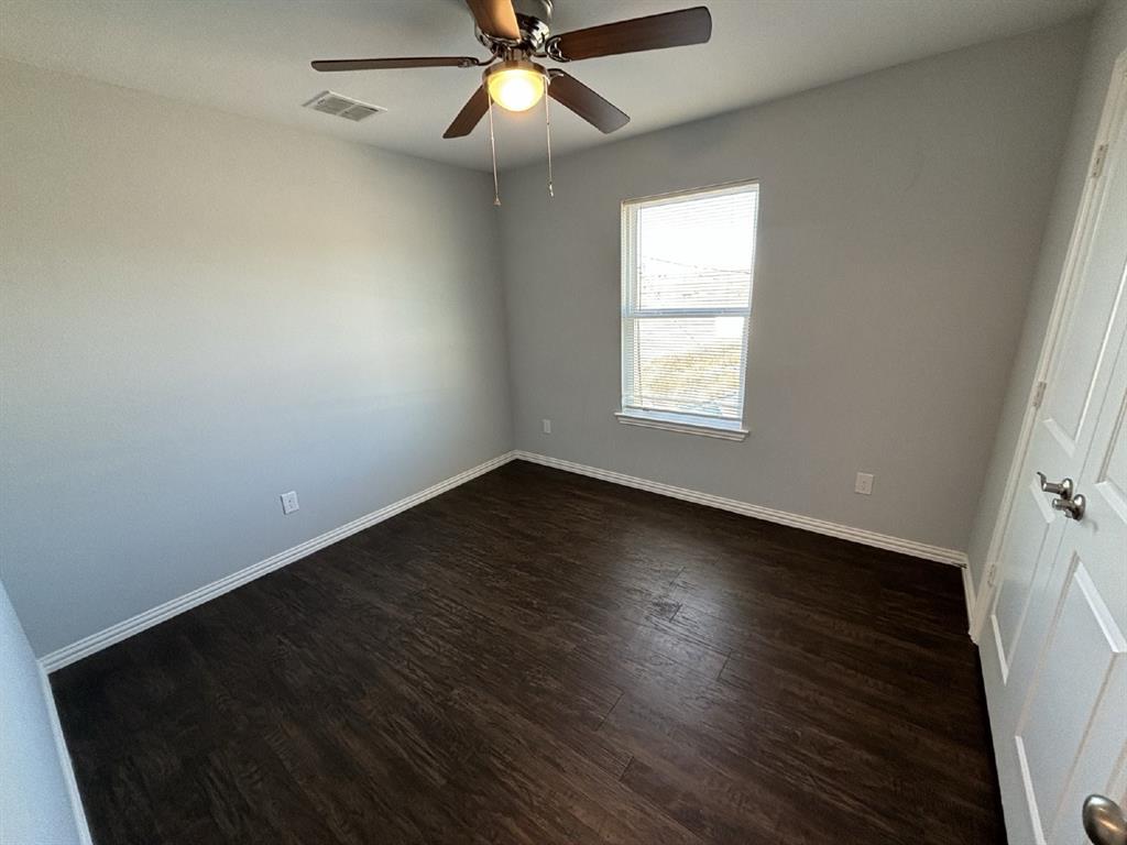 108 Arrowhead Street, Unit B Fort Worth, TX 76108 - Photo 15 of 17 an empty room with wooden floor fan and windows