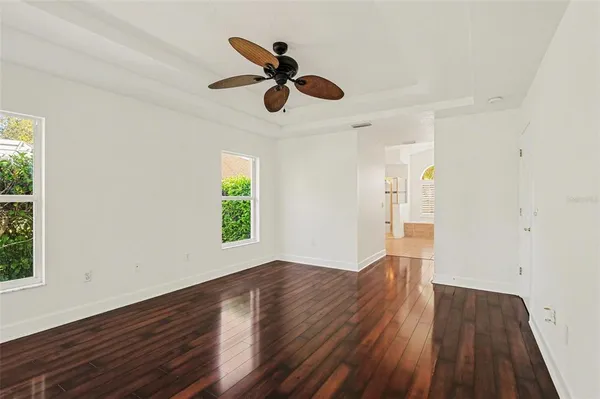 a view of empty room with wooden floor and fan