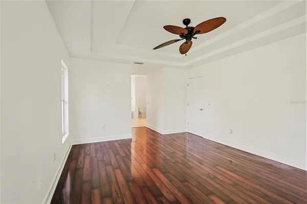 an empty room with wooden floor and ceiling fan