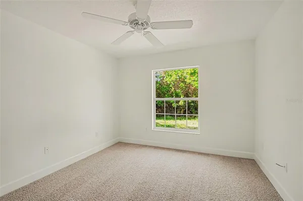 an empty room with a window and a fan