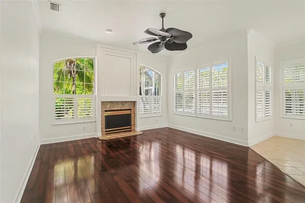 a view of an empty room with wooden floor fireplace and a window