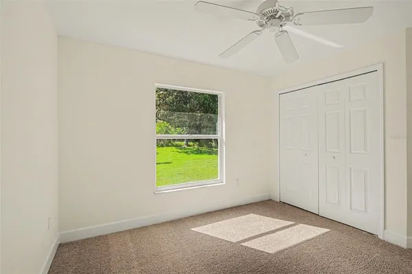 an empty room with windows and fan