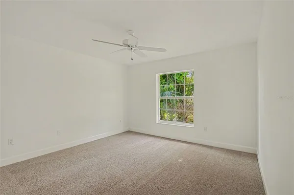 an empty room with a window and a ceiling fan