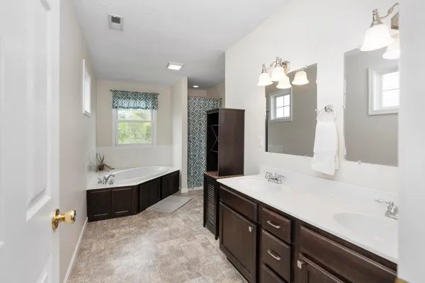 a bathroom with a sink double vanity granite tub shower and a mirror