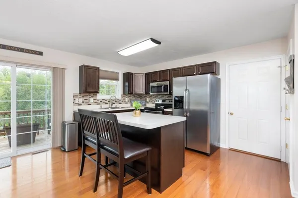 a kitchen with a refrigerator a stove a sink dishwasher with a dining table and wooden floor